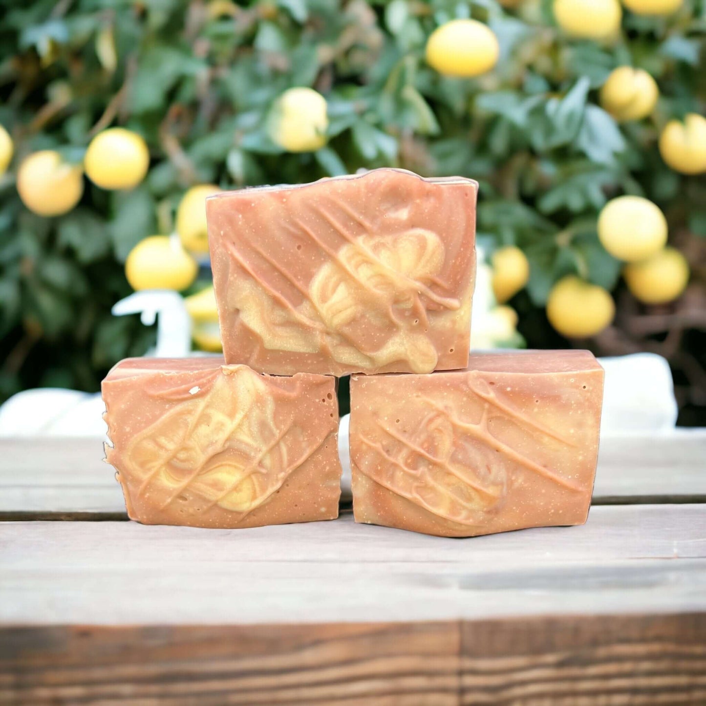 Artisanal citrus-infused tallow soap bars with detailed embossing, presented on a wooden table with lemon tree background