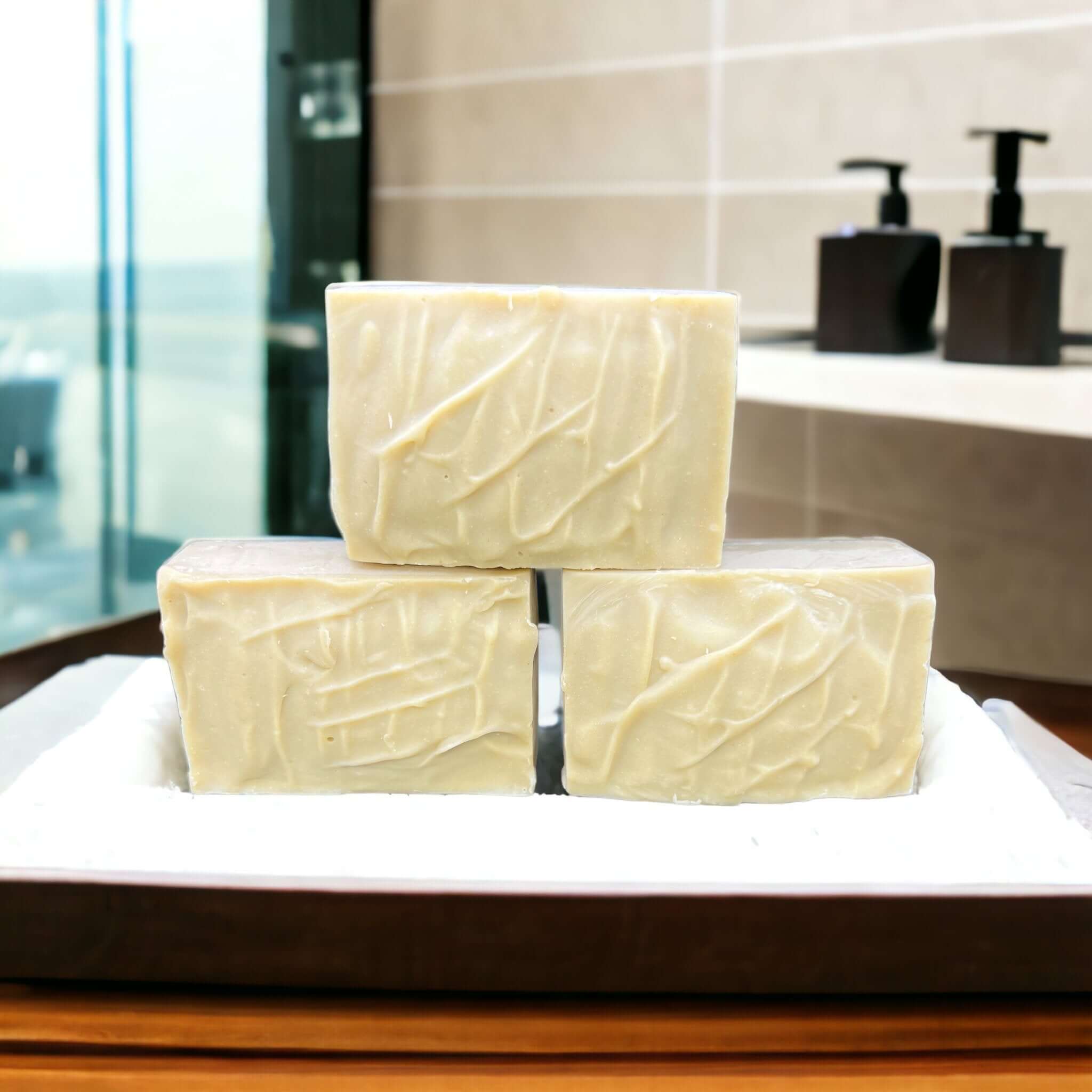 Three stacked bars of textured, creamy white soap.