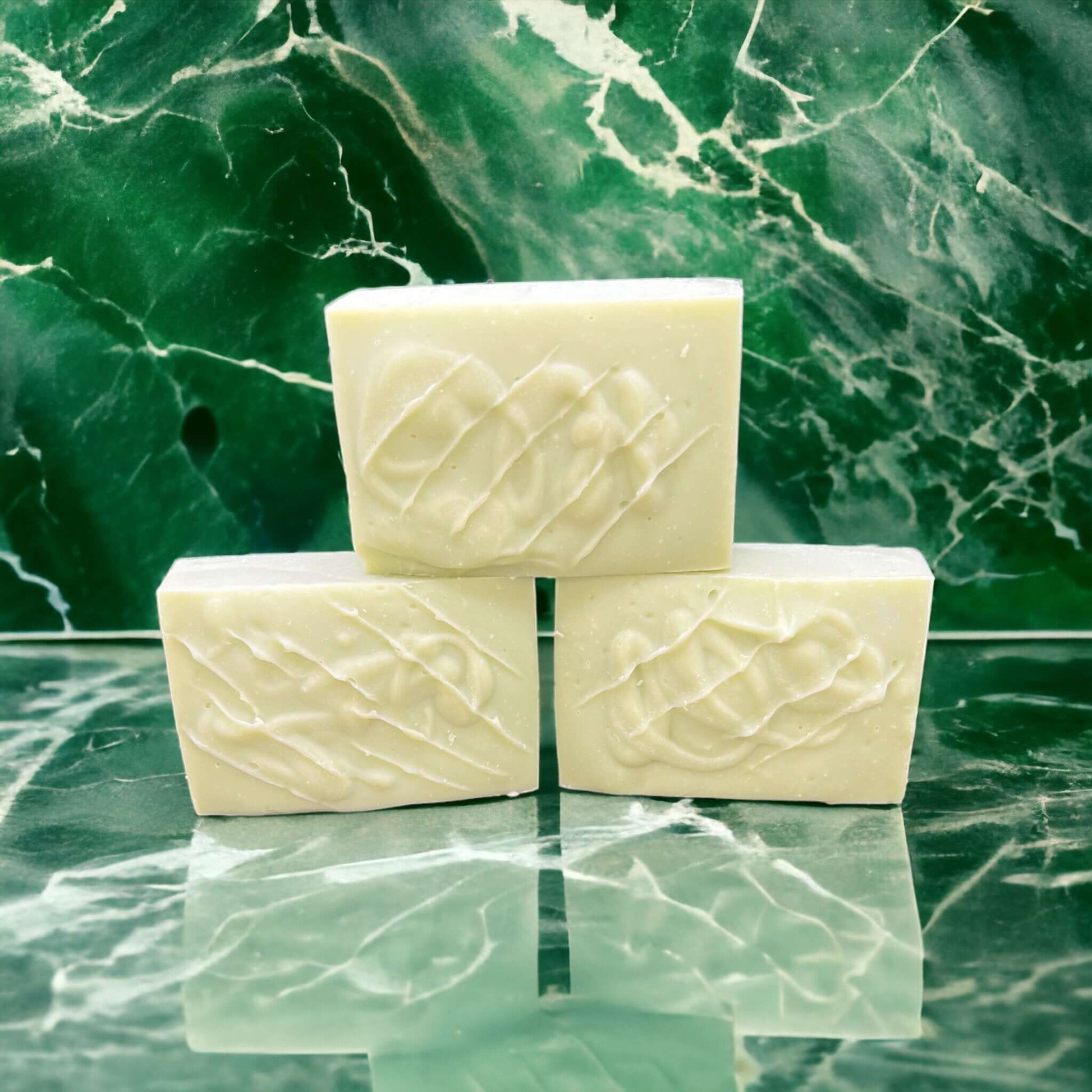 Handcrafted tallow soap bars with embossed design on a green marble surface, reflecting natural artisanal skincare